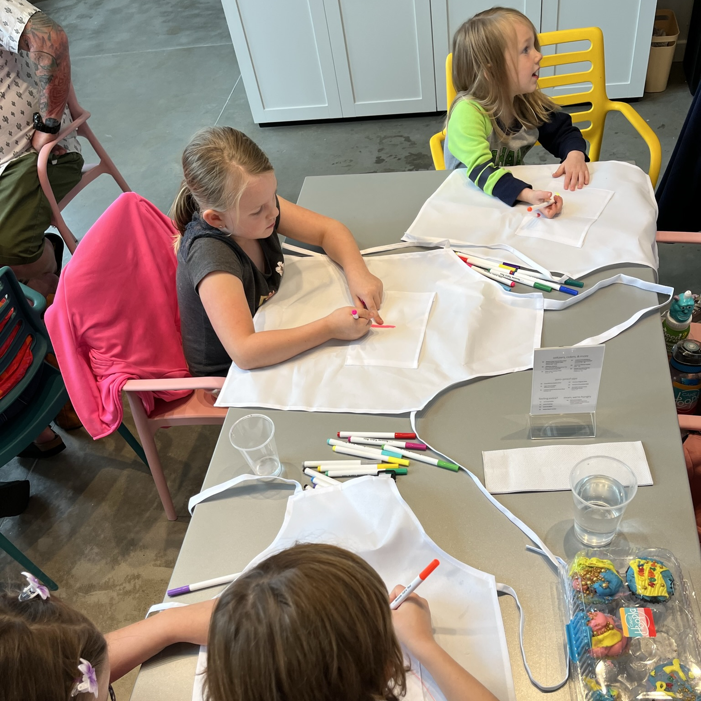 A table of kids decorates white aprons before diving into cupcake-decorating during a cupcake-decorating party at Cake Hoopla in Tigard, near Portland.