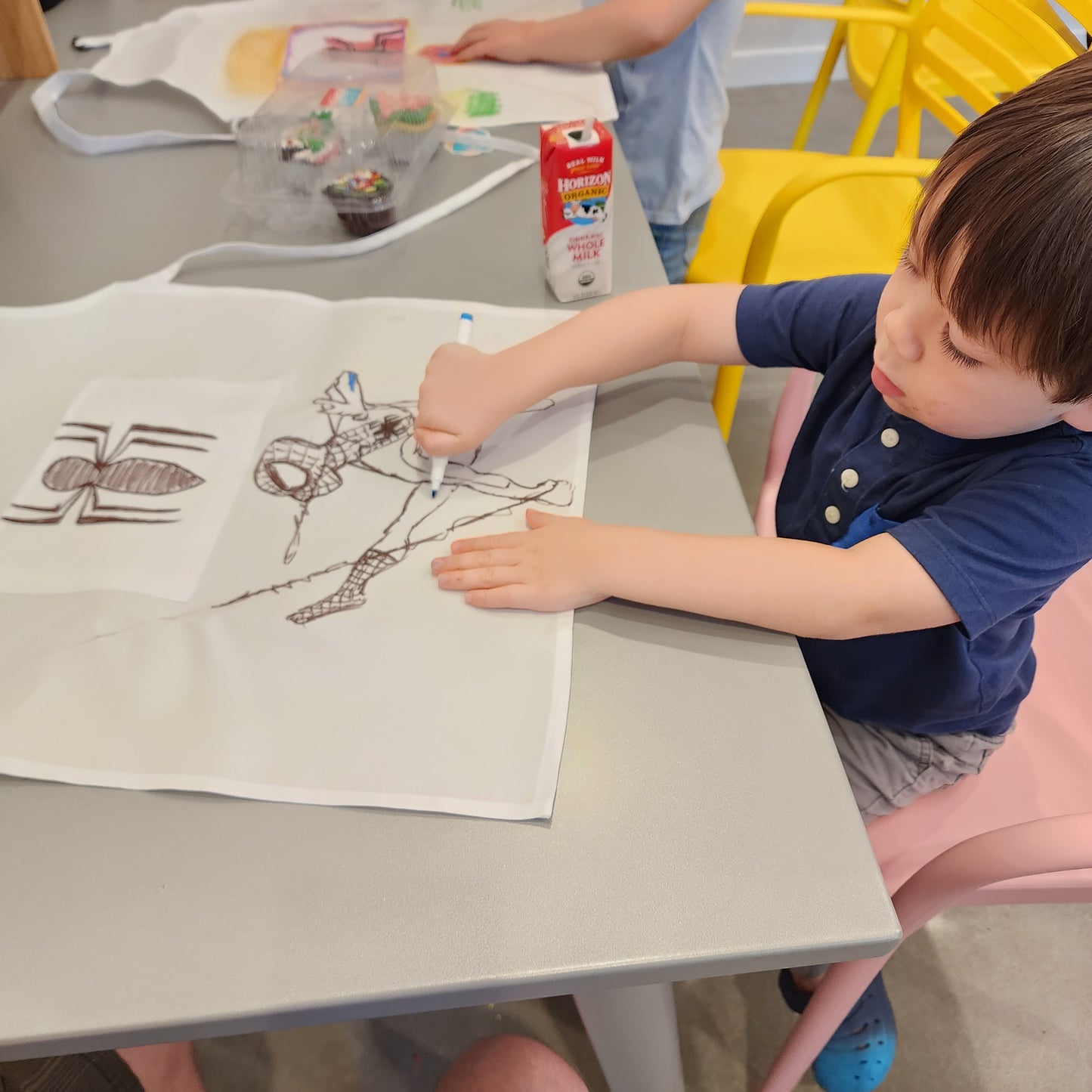 A young boy colors an apron with fabric markers during an in-studio cupcake-decorating party at Cake Hoopla in Tigard, near Portland.