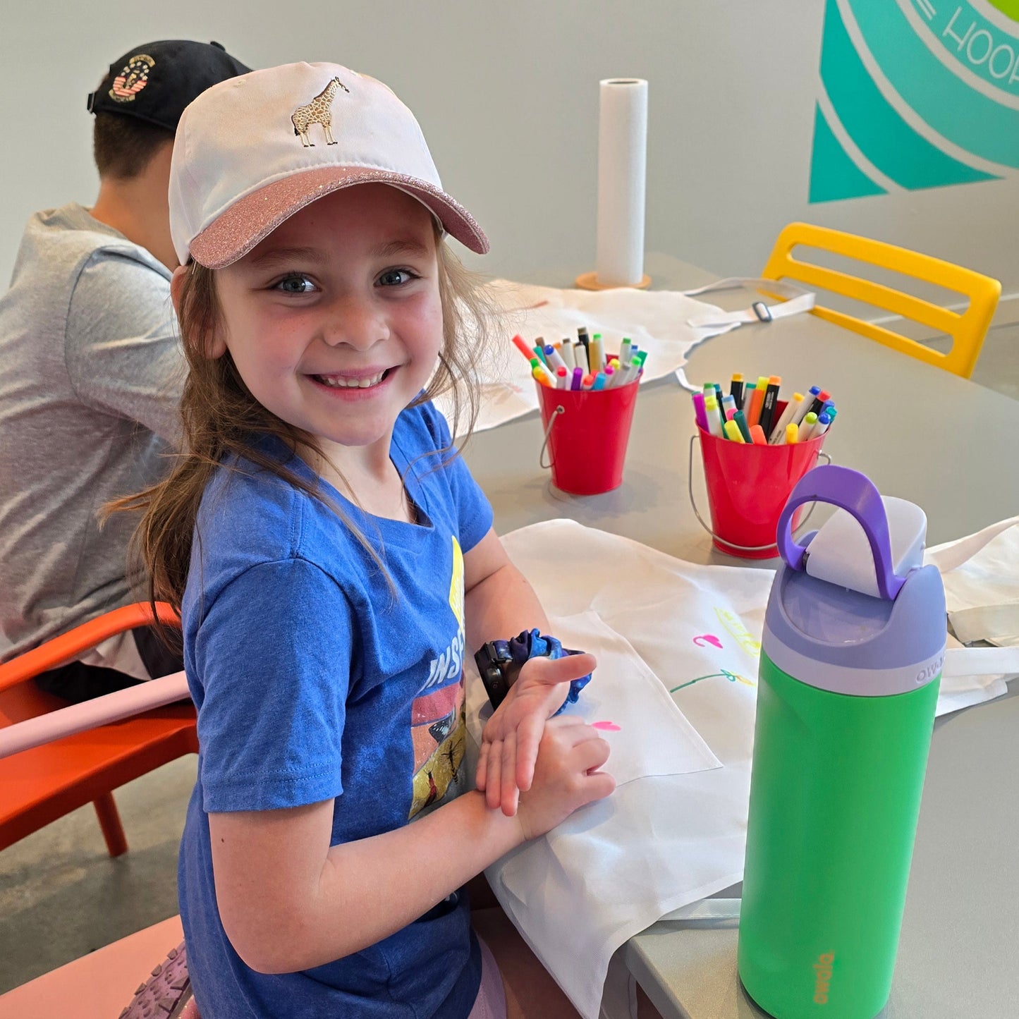 Happy girl colors her white apron at Cake Hoopla's cake camp in Tigard, near Portland.