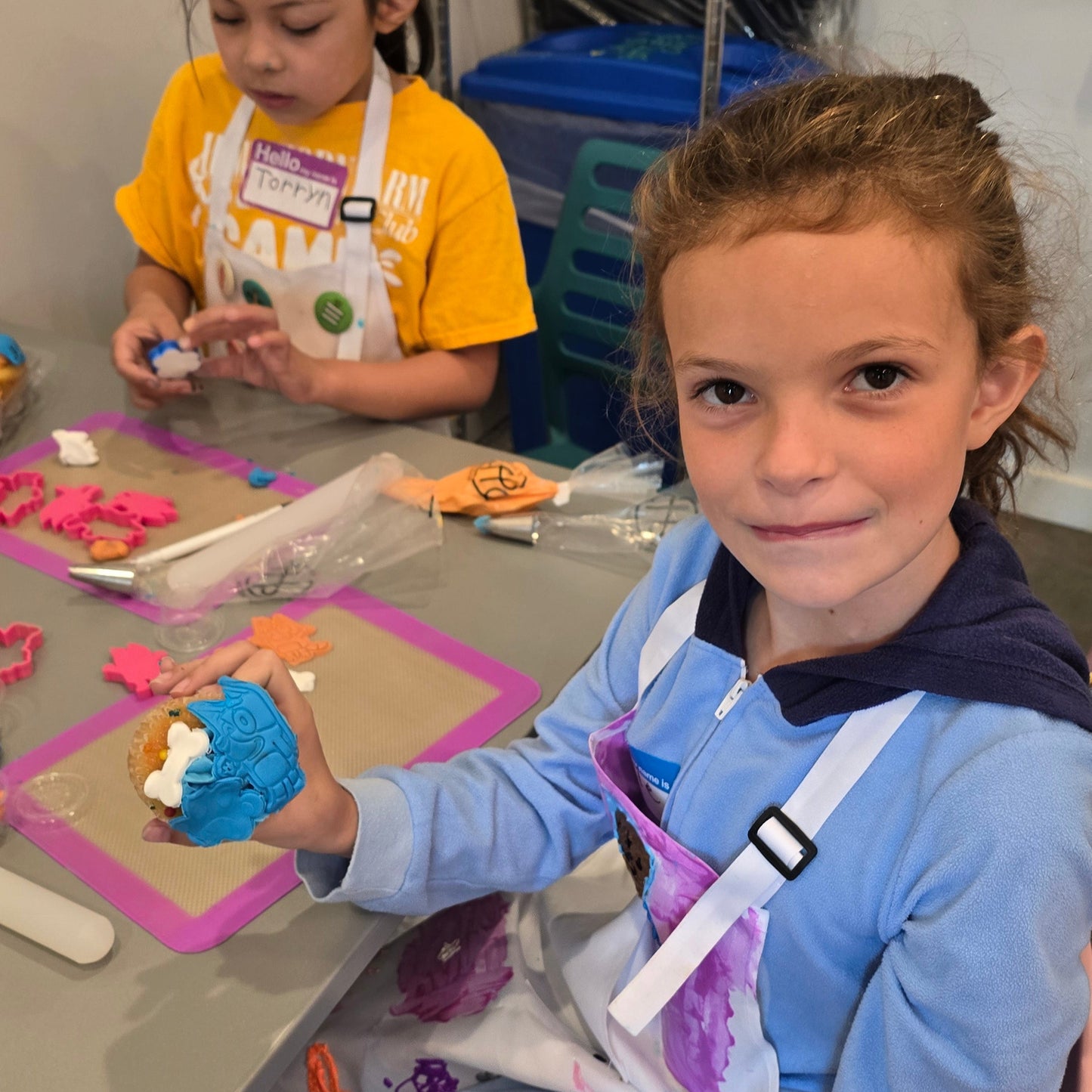 Girls decorating Bluey-themed cupcakes at Cake Hoopla's cake camp.