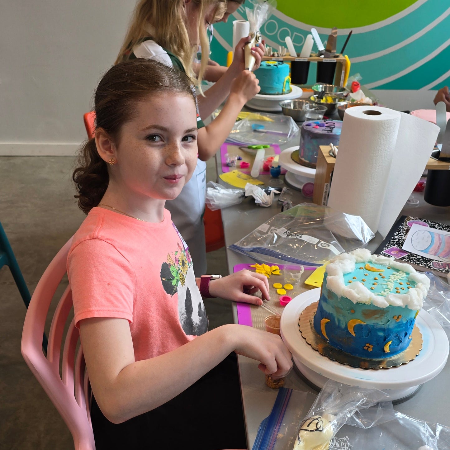 A table of kids decorates cakes, including a moon cake, at cake camp at Cake Hoopla in Tigard near Portland.