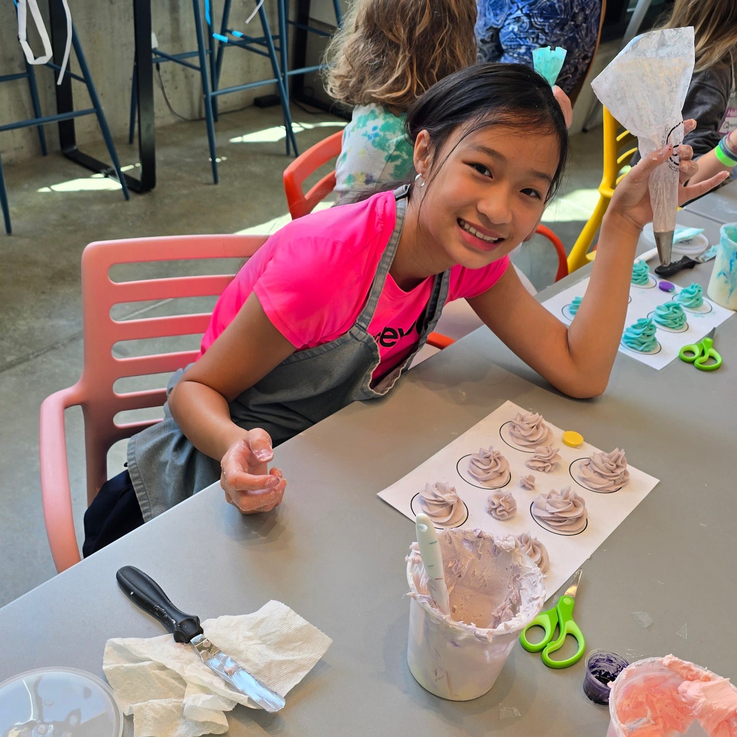 A girl holds a piping bag to practice piping techniques at cake camp at Cake Hoopla in Tigard near Portland.