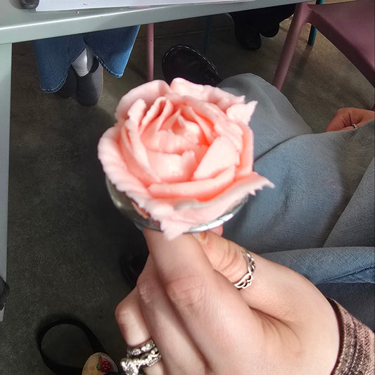 Woman shows off pink buttercream rose on frosting nail at Cake Hoopla in Tigard, near Portland.