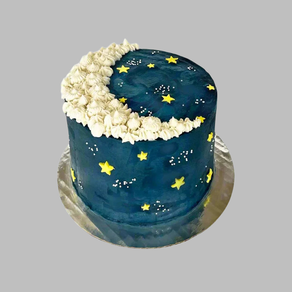 To The Moon cake decorated like a night sky with a white crescent moon, yellow stars, and sprinkle galaxies, available as a DIY cake-decorating kit during open studio time or to-go or as a pre-decorated kit from Cake Hoopla in Tigard, Oregon near Portland