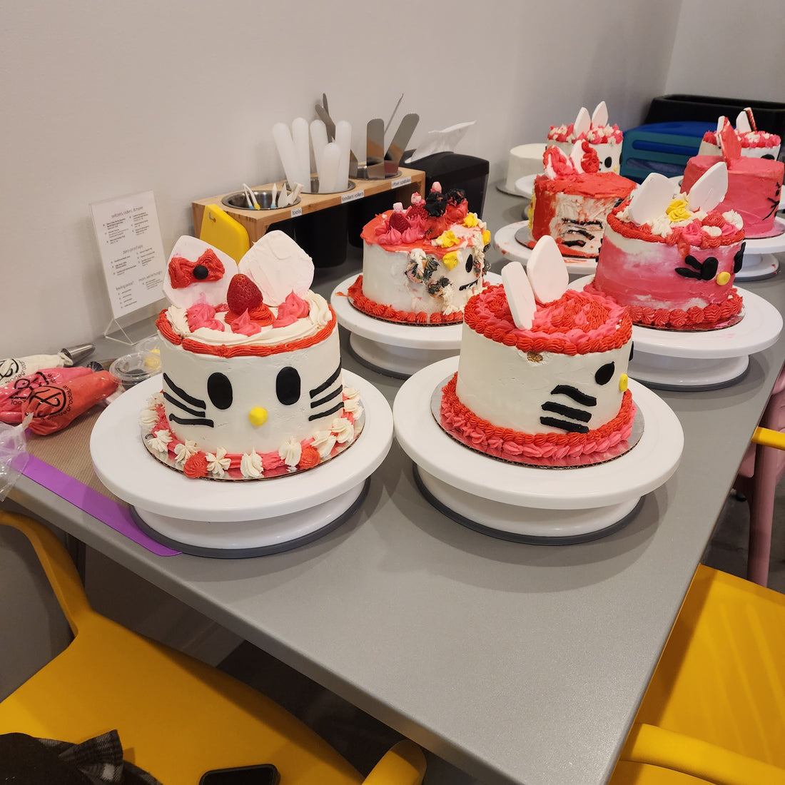 A table filled with custom Hello Kitty cakes decorated during a DIY cake-decorating party, each unique.