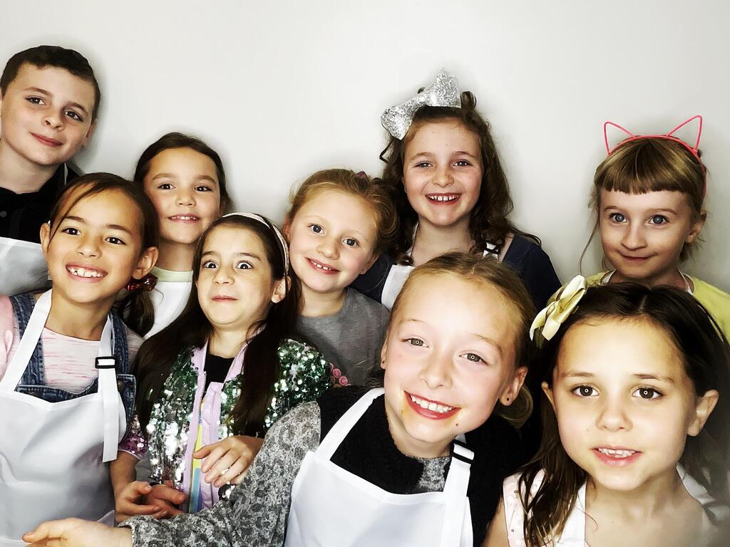 A group of kids celebrate a birthday party at Cake Hoopla in Tigard, Oregon near Portland, and use the Photo Booth station to take pictures wearing their white aprons.