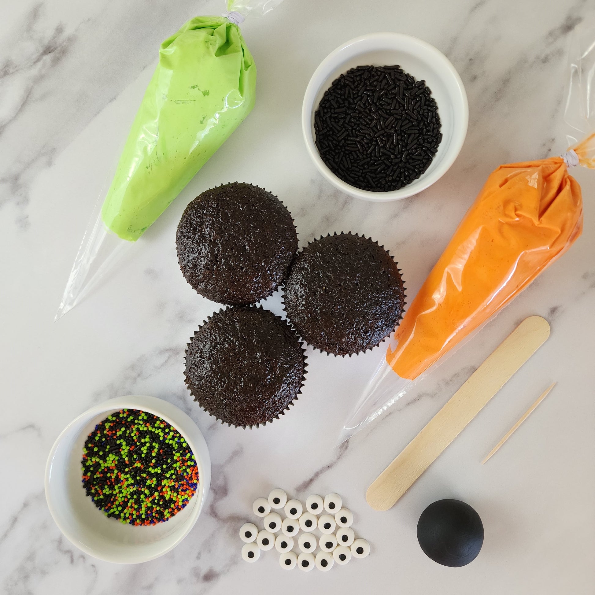 Components of Halloween-themed  DIY cupcake-decorating kit including green and orange frosting, cupcakes, sprinkles, googly eyes, and fondant available at Cake Hoopla during open studio time in Tigard, Oregon near Portland.