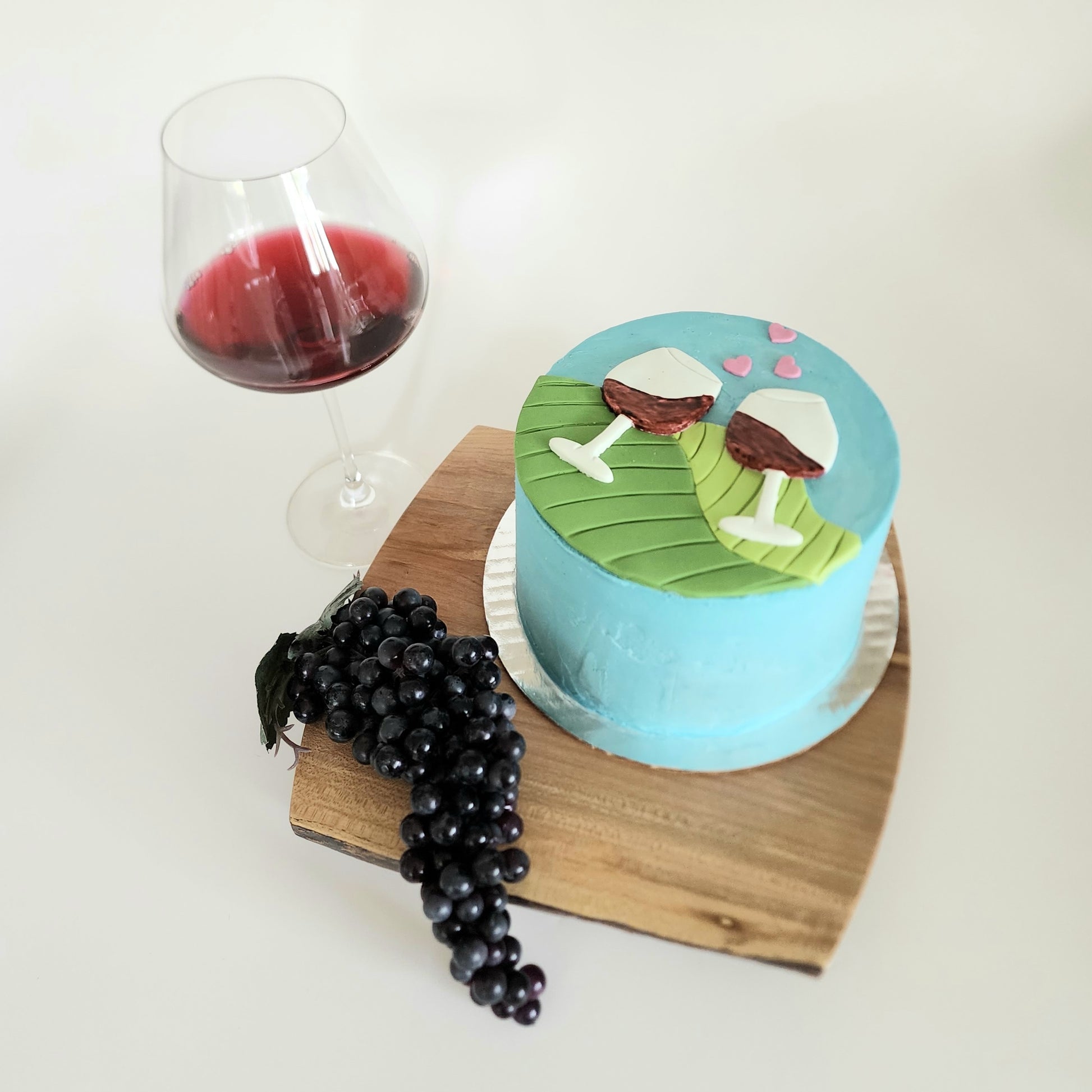 wine-themed cake with a bunch of grapes and pinot noir glass nearby