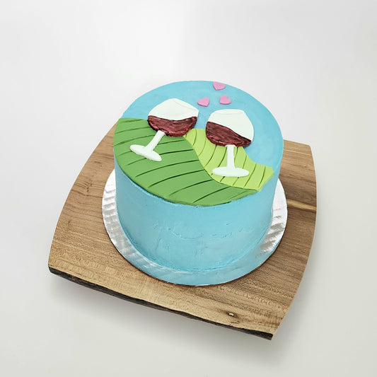 wine-themed cake with blue background, rolling green hills, two pinot noir glasses chinking, and pink hearts drifting above the glasses