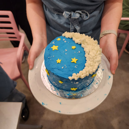 At the Cake Hoopla DIY cake/cupcake-decorating studio, a middle school age kid learned to frost a cake blue, then added a white frosting crescent moon and yellow fondant stars.