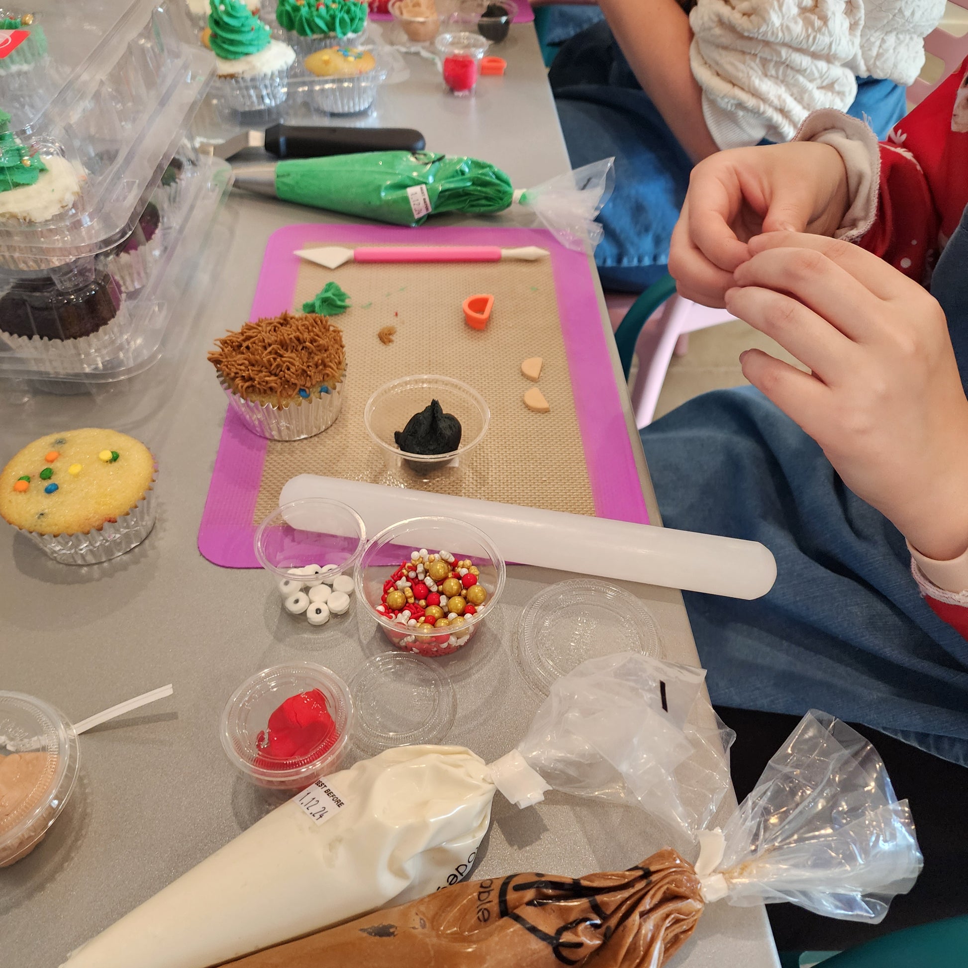 A kid decorating cupcakes like teddy bears and Christmas presents during a holiday DIY cupcake-decorating class at Cake Hoopla in Tigard, Oregon near Portland.