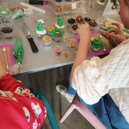 Families decorating cupcakes like teddy bears and Christmas presents during a holiday DIY cupcake-decorating class at Cake Hoopla in Tigard, Oregon near Portland.