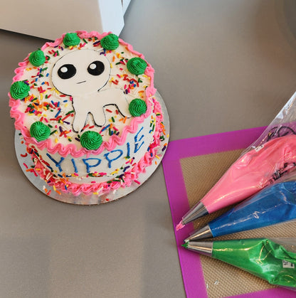 A unique cake decorated with a white monster, pink, blue, and green frosting, and rainbow sprinkles. Decorated during open studio time with the create-your-own option.