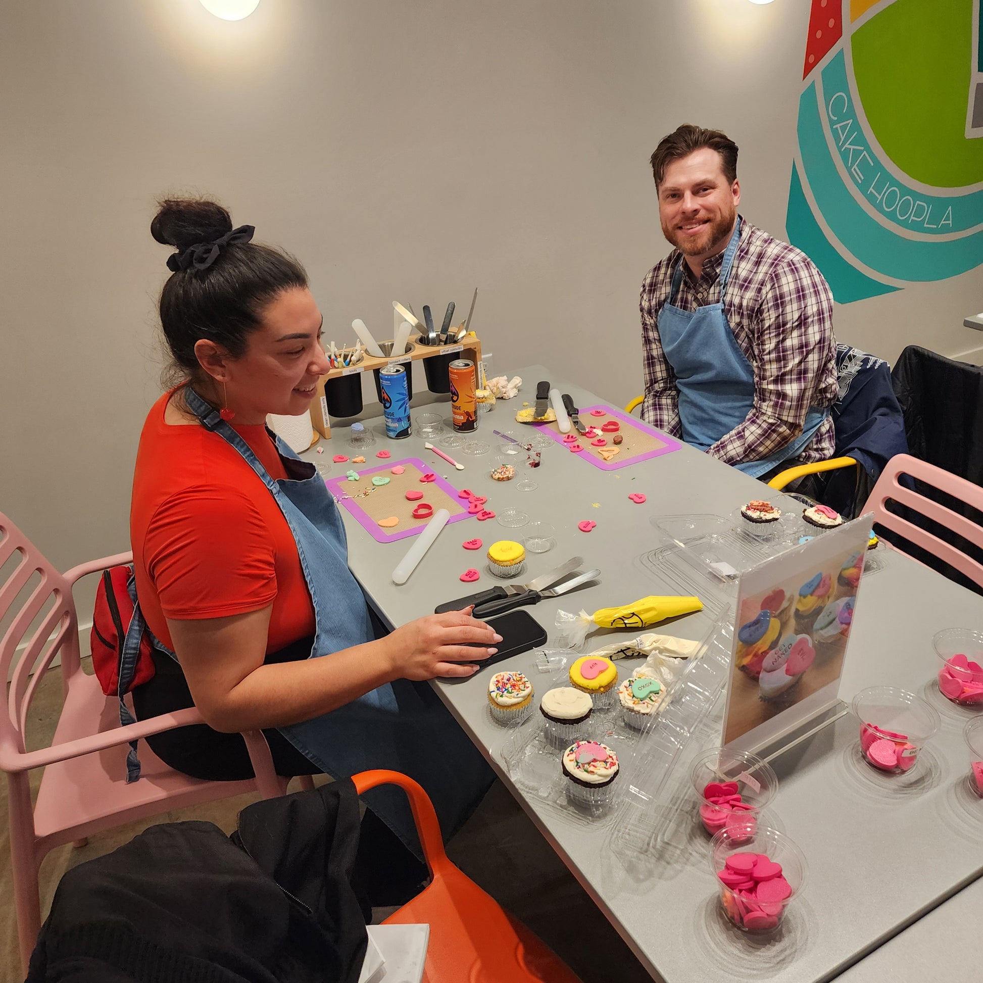 A couple decorates cupcakes together at Cake Hoopla in the Portland area during a cake-decorating workshop.