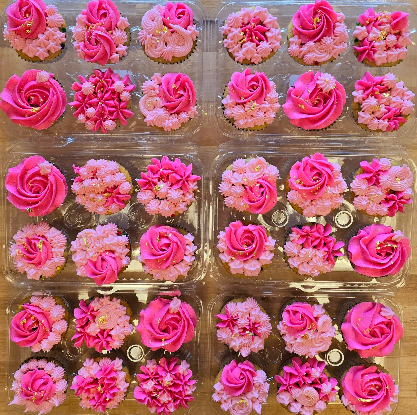 Pink floral-themed cupcakes decorated with light and dark pink rosettes and stars and gold leaf; pre-decorated cupcakes available for pick up at Cake Hoopla in Tigard, Oregon, in the Portland area.