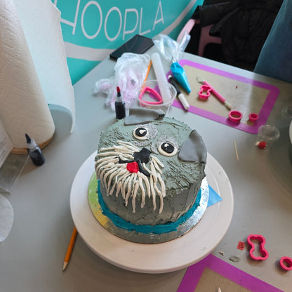 A customer decorated a gray terrier dog came during a do-it-yourself cake-decorating workshop at Cake Hoopla. The dog is gray with a white beard, folded ears, and a red tongue. 