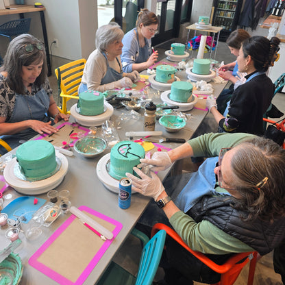 A group of women decorates cakes together at Cake Hoopla in the Portland area during a cake-decorating workshop.