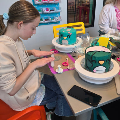 A middle-school age kid rolls out fondant as she decorates a bird-themed cake at Cake Hoopla's DIY cake-decorating studio.