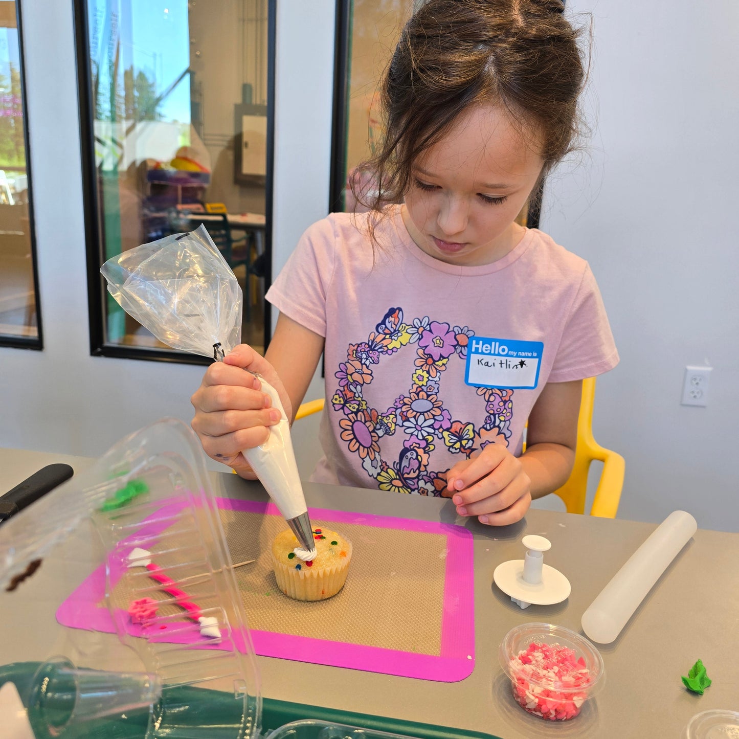 A girl concentrates on decorating a white cupcake during open studio time at Cake Hoopla in Tigard, Oregon in the Portland area.