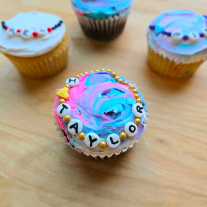 Friendship-bracelet-themed cupcake decorated at Cake Hoopla in Tigard, Oregon near Portland as a DIY cupcake-decorating kit, with the word "TAYLOR" written on it.