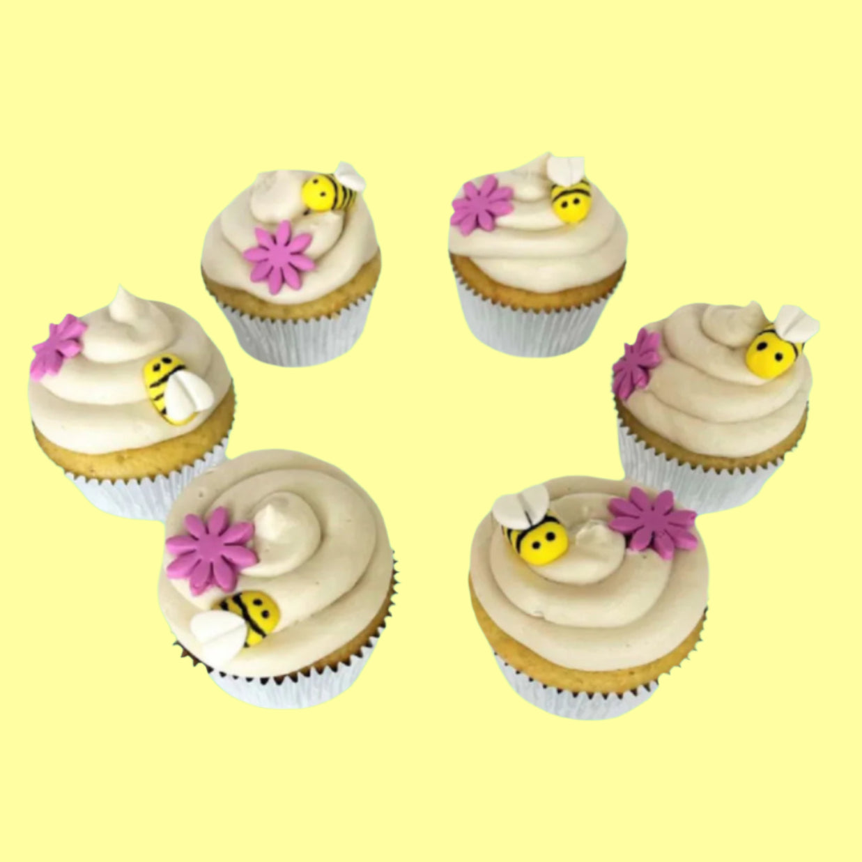 Bee-themed cupcakes frosted in white with yellow and black bumble bees and pink flowers on top; a DIY cupcake kit available to decorate during open studio time at Cake Hoopla in Tigard, Oregon, in the Portland area.