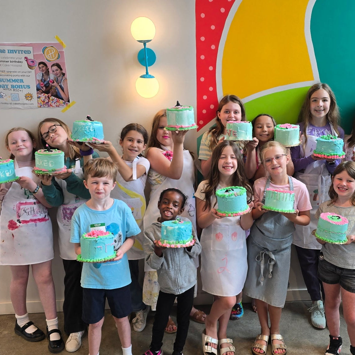 A group of kids show off their practice cakes decorated during cake camp.