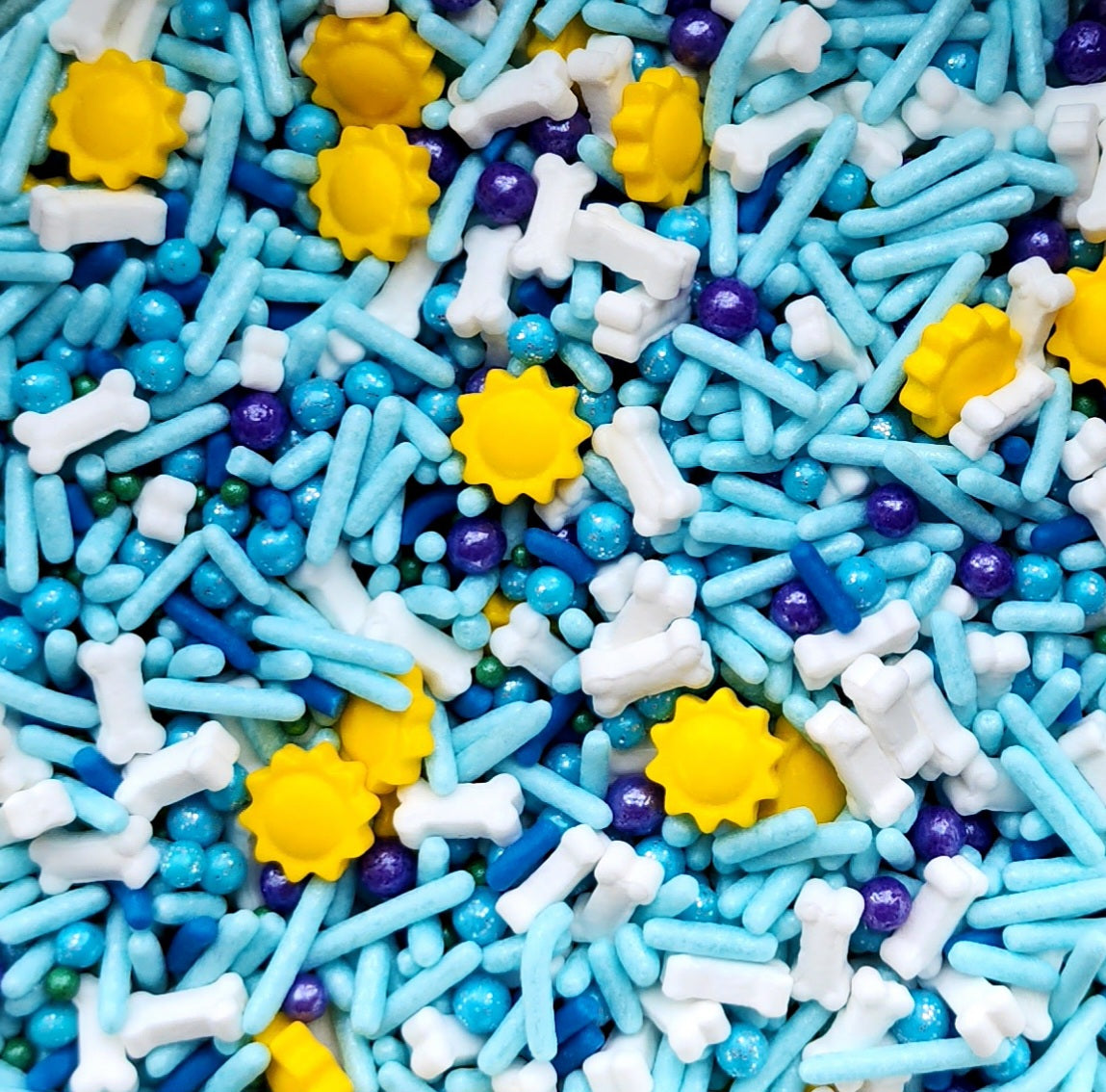 Colorful sprinkles with blue, yellow, white, and purple shapes as a custom sprinkle mix available with Cake Cart rental in the Portland area.