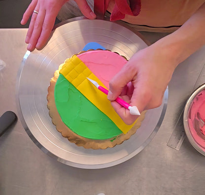 A person decorates a Wicked-themed cake by making a yellow brick road from fondant using fondant tools at a cake-decorating class in Tigard, near Portland.