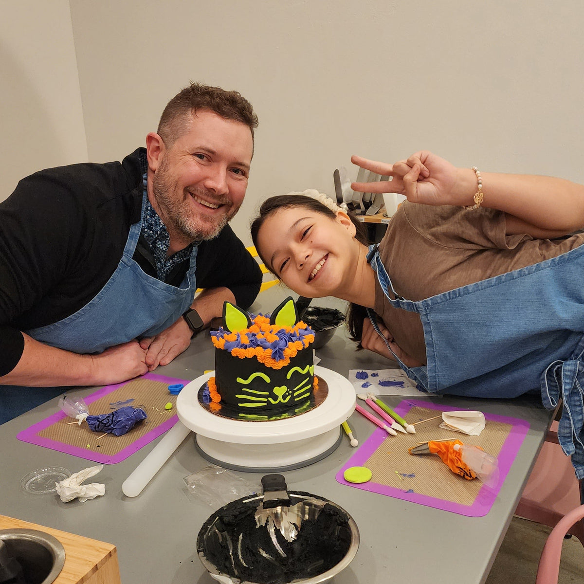A father and daughter show off their Halloween black cat cake decorated at Cake Hoopla in Tigard, near Portland.