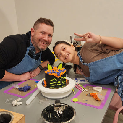 A father and daughter show off their Halloween black cat cake decorated at Cake Hoopla in Tigard, near Portland.