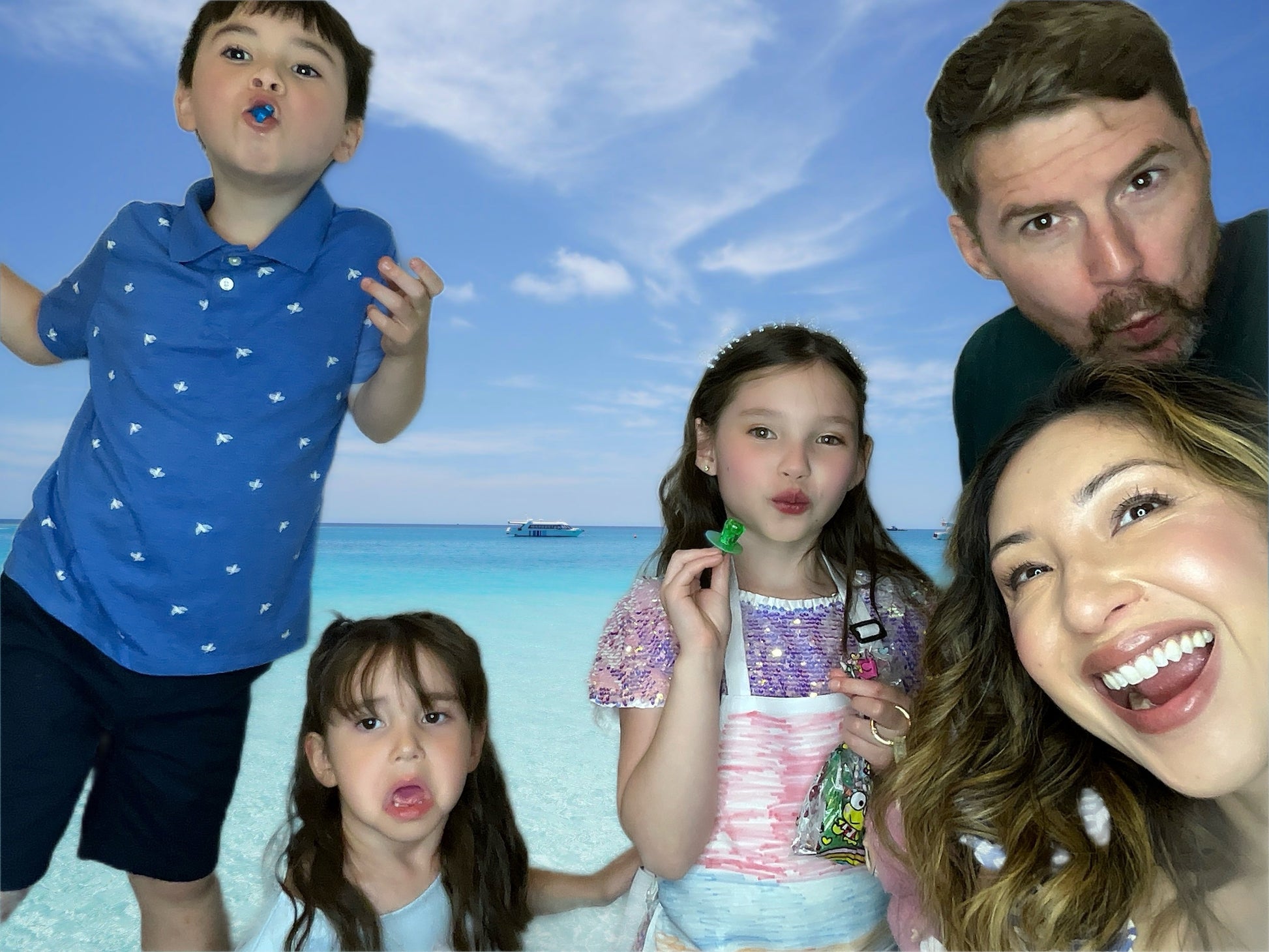 A family of 5 take photos in front of a tropical ocean backdrop.