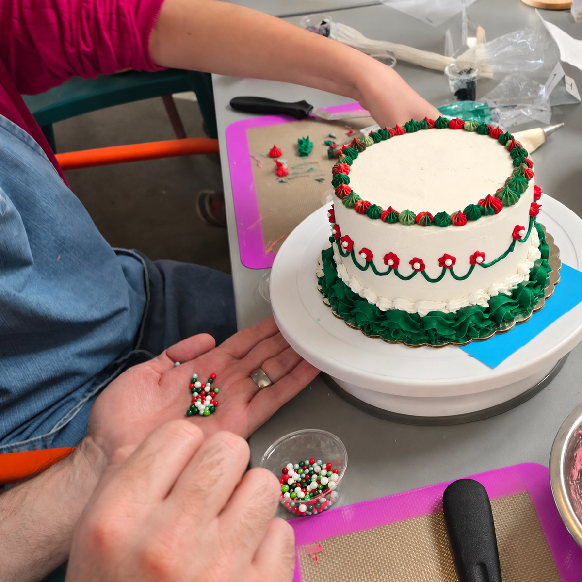 Customers decorate a Christmas-themed vintage cake with red, green, and white frosting, and sprinkle pearls.