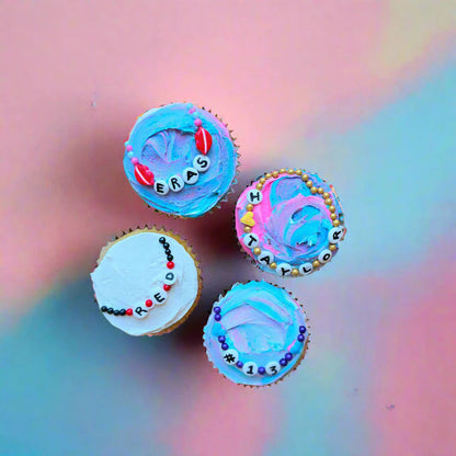 Friendship-bracelet-themed cupcakes decorated at Cake Hoopla in Tigard, Oregon near Portland as a DIY cupcake-decorating kit, with the words "ERAS," "I LOVE TAYLOR," and "RED" written on them.