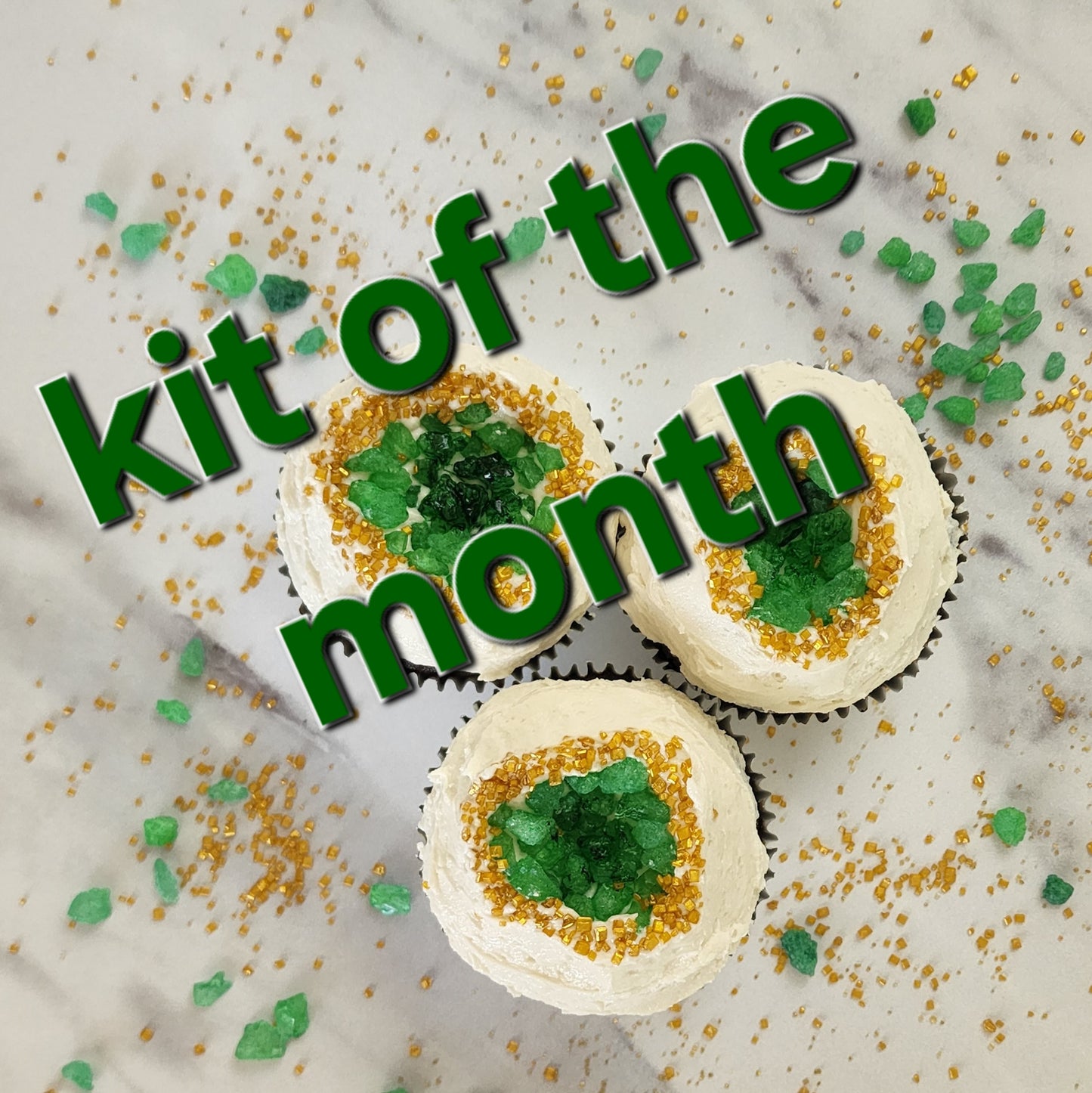 Decorative cupcakes with green and gold sprinkles on a marble surface, featuring text 'kit of the month'.