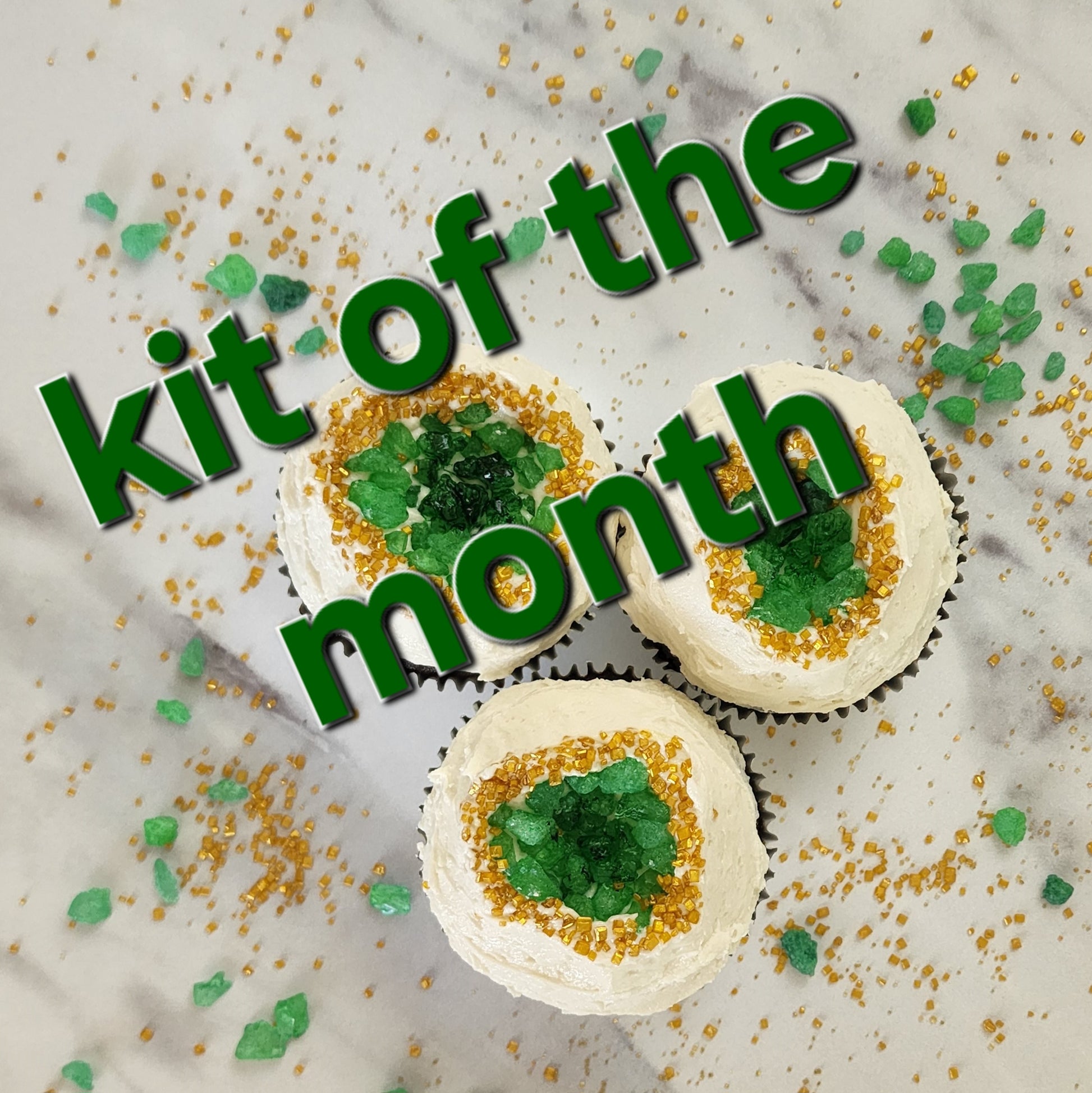 Decorative cupcakes with green and gold sprinkles on a marble surface, featuring text 'kit of the month'.
