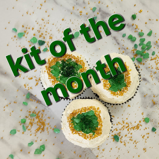 Decorative cupcakes with green and gold sprinkles on a marble surface, featuring text 'kit of the month'.