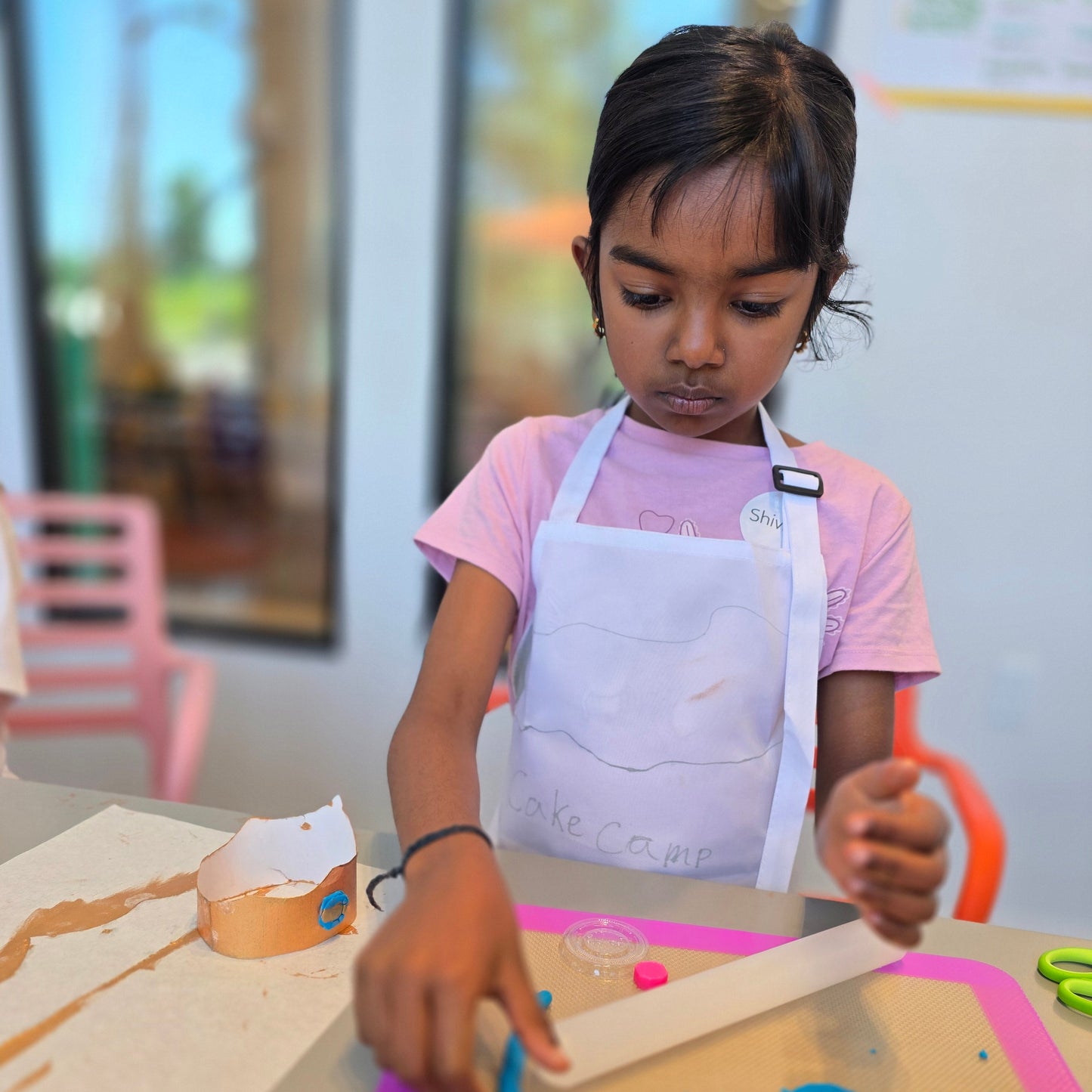 Girl makes an edible frosting and fondant crown at summer cake camp.
