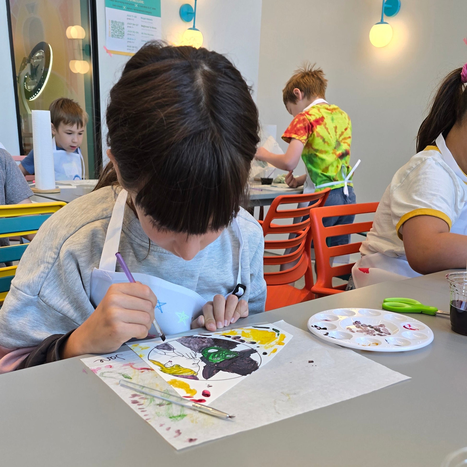 Girl paints Wicked themed sugar art in bright studio around other Cake Hoopla summer cake campers.
