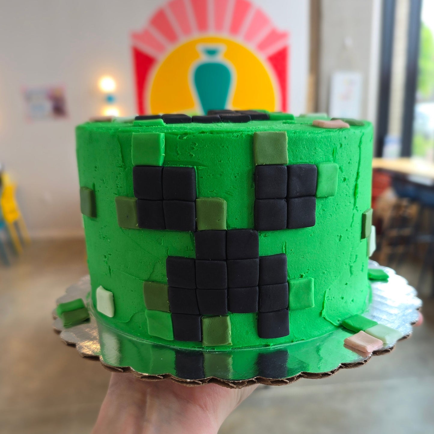 Minecraft-themed cake, green with square fondant cutouts to form a Creeper face.
