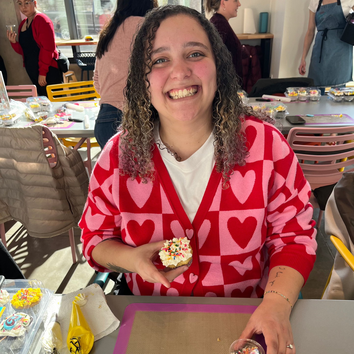 a woman shows off her Valentine's Day themed cupcake at a DIY cake-decorating class at Cake Hoopla in Tigard, near Portland