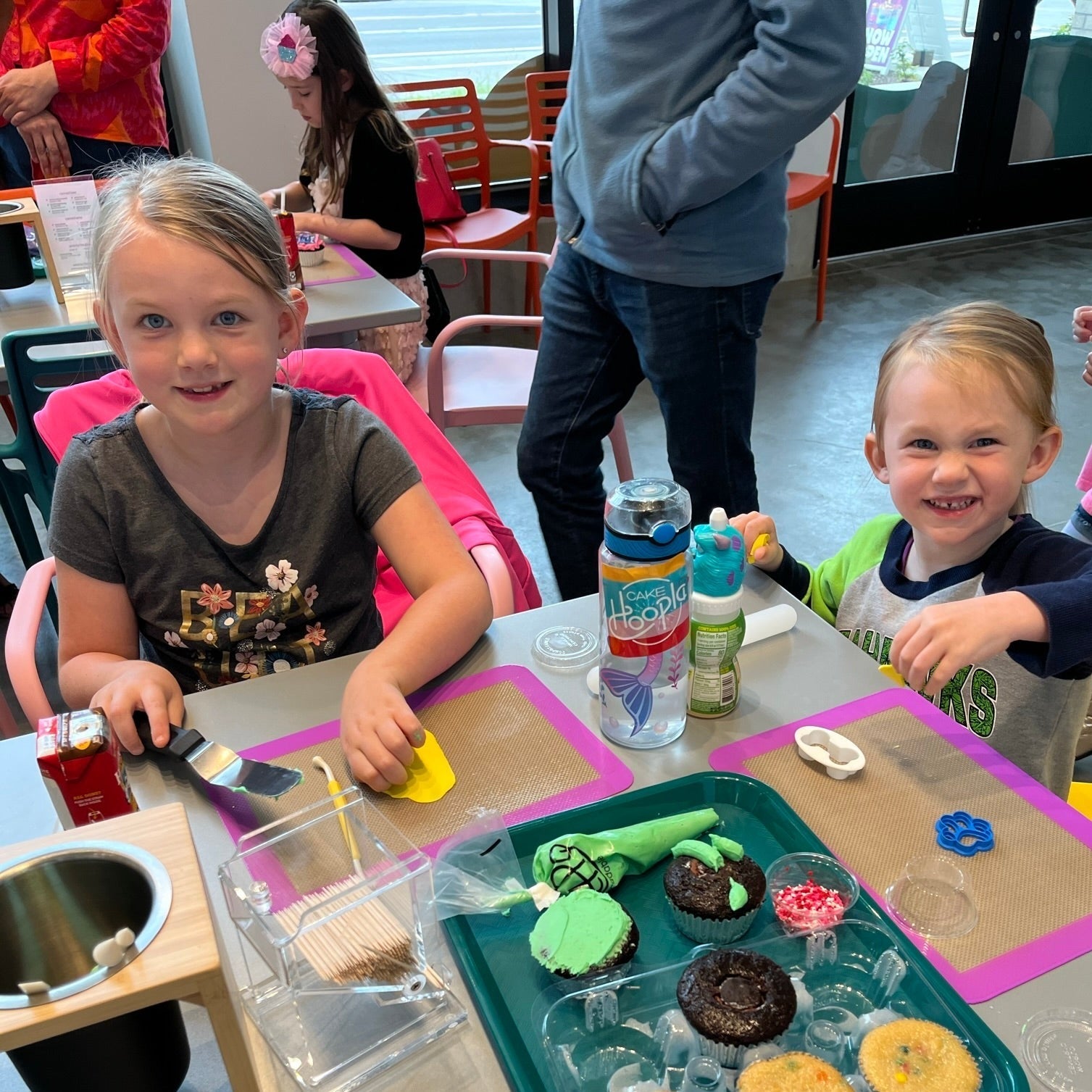 Two little girls roll out fondant to top their cupcakes from their Create Your Own Cupcake Kit during  time at Cake Hoopla in Tigard, Oregon near Portland.