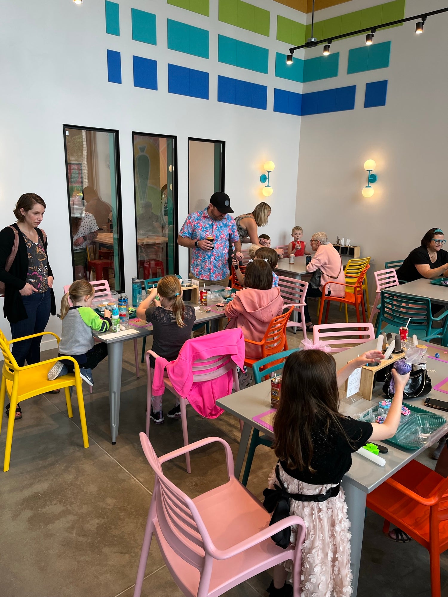 Tables of people of all ages enjoy cupcake-decorating during a whole-studio party at Cake Hoopla in the Portland area.