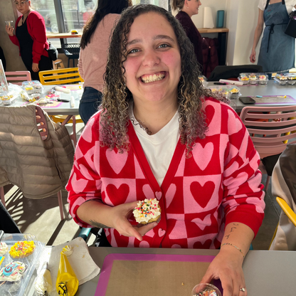 a woman shows off her Valentine's Day themed cupcake at a DIY cake-decorating workshop at Cake Hoopla in Tigard, near Portland