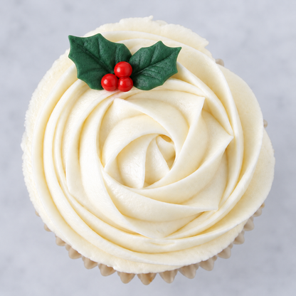A white frosting rosette across a cupcake with two small holly leaves and three berries at the top.