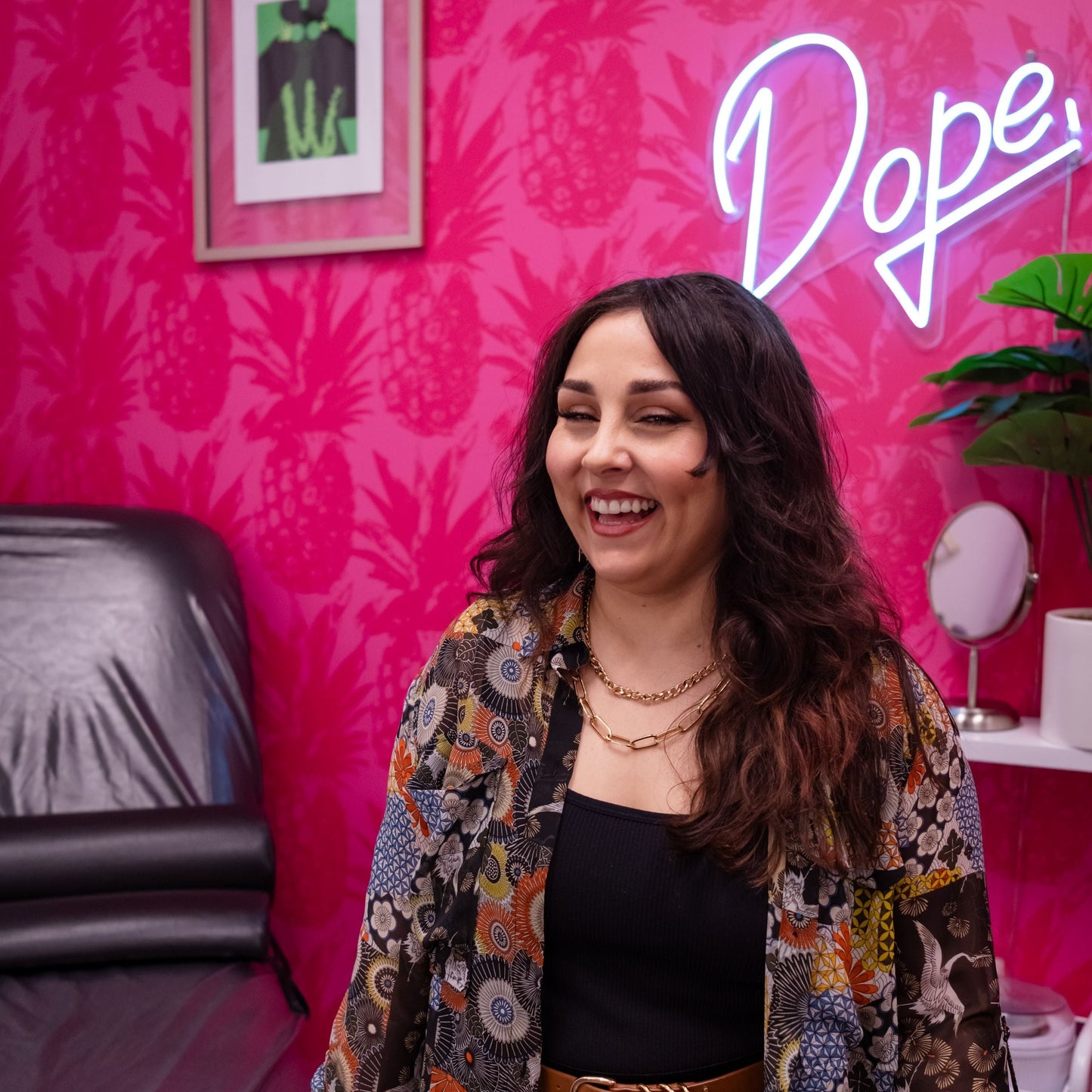Jena from Magix in the Makeup standing in a room with pink walls and a 'Dope' sign.