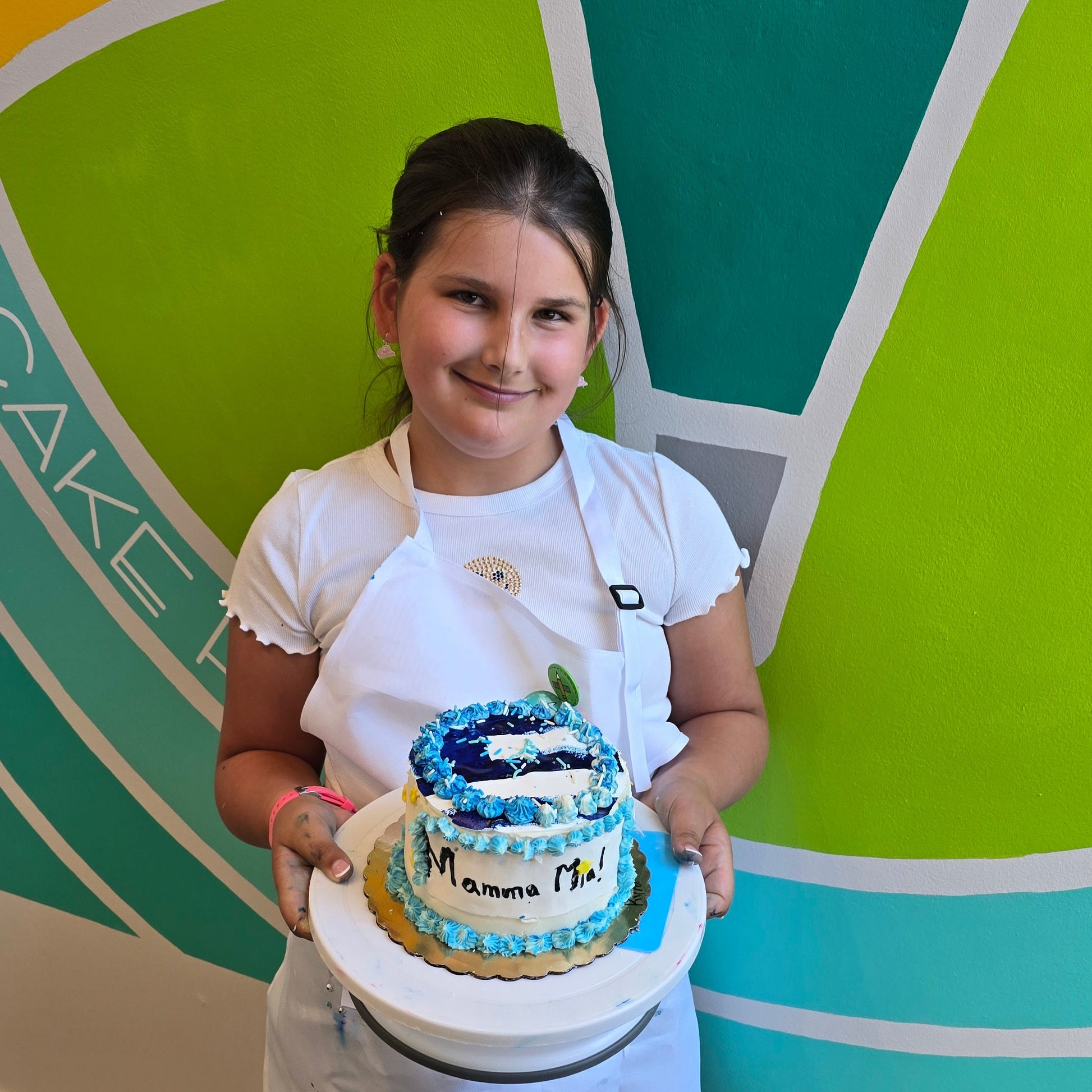 Girl proudly shows off her Mama Mia cake made during summer cake camp at Cake Hoopla.
