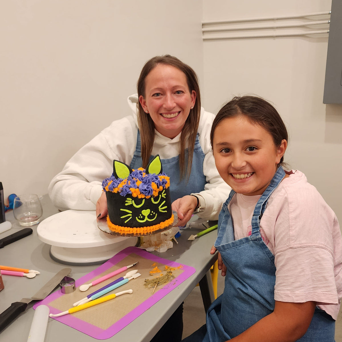 A mom and daughter show off their Halloween black cat cake decorated by them at Cake Hoopla in Tigard, near Portland.