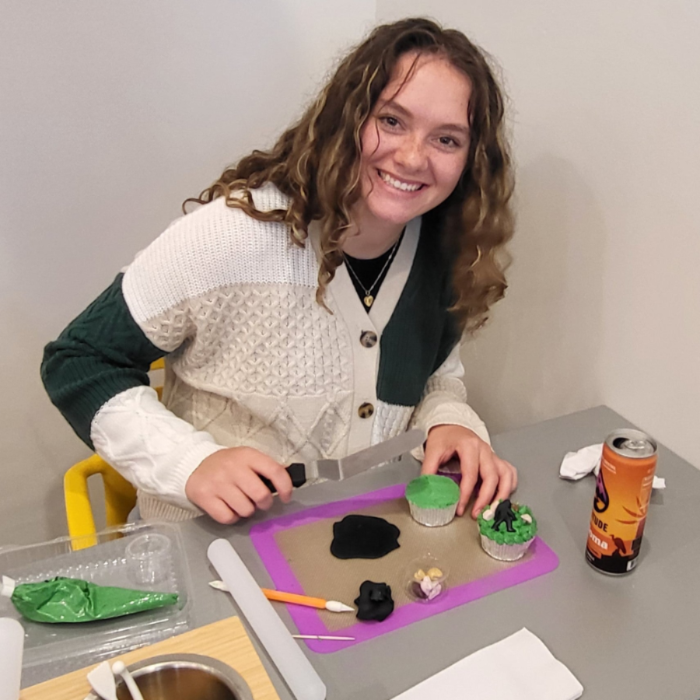 Person decorating cupcakes with tools and ingredients on a table at Cake Hoopla in Tigard, near Porltand.