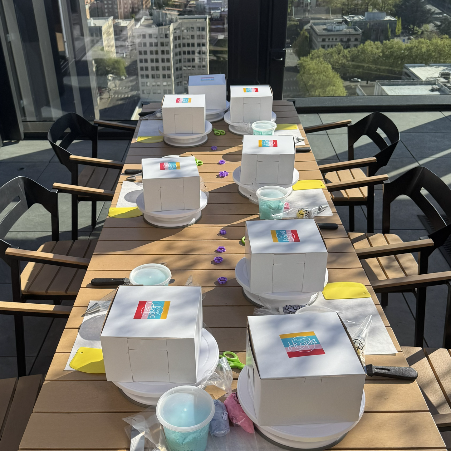 Outdoor dining table set up with cake boxes and decorating supplies on terrace in Portland, Oregon.
