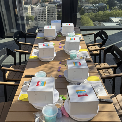 Outdoor dining table set up with cake boxes and decorating supplies on terrace in Portland, Oregon.